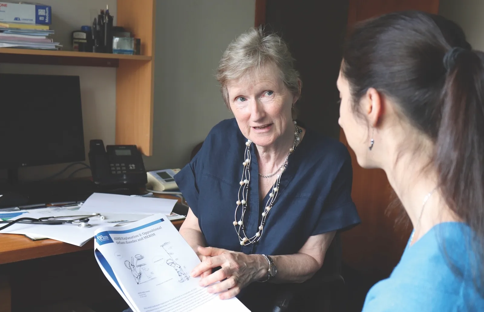 Dr. Alison Poulton talking through an ADHD explanation sheet with a patient in her consulting room